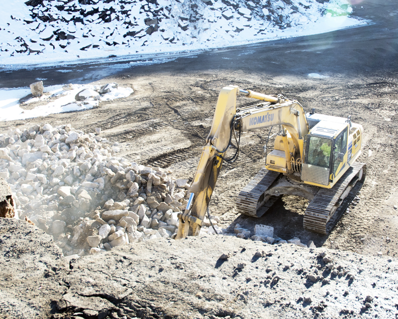 Excavator handling concrete rubble at a recycling yard
